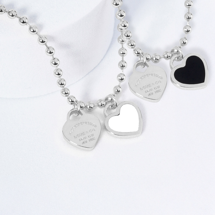 Silver necklace with heart-shaped charms on a white background
