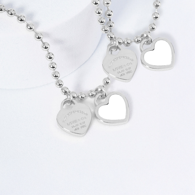 Silver necklace with heart-shaped pendants on a white background