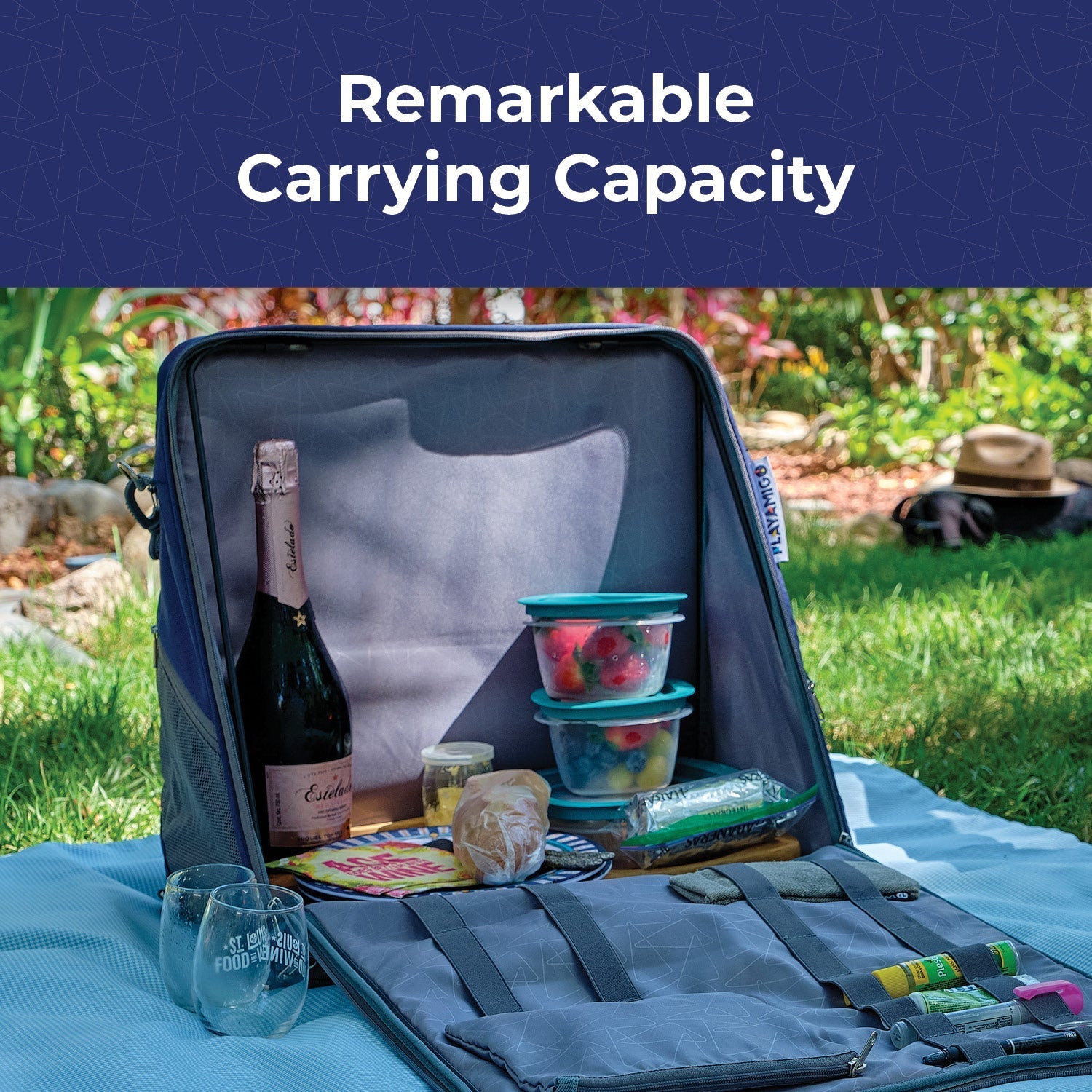 Open picnic bag with food items and a bottle of wine on a grassy outdoor setting.