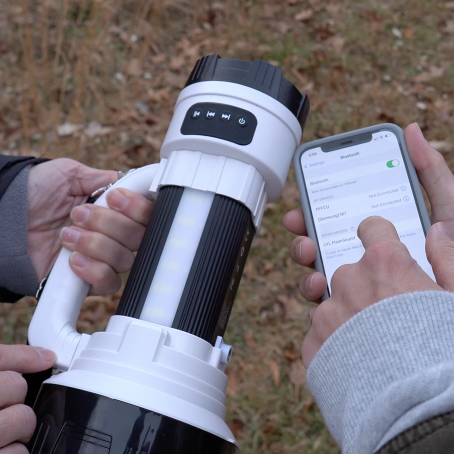 Person holding a flashlight and using a smartphone outdoors