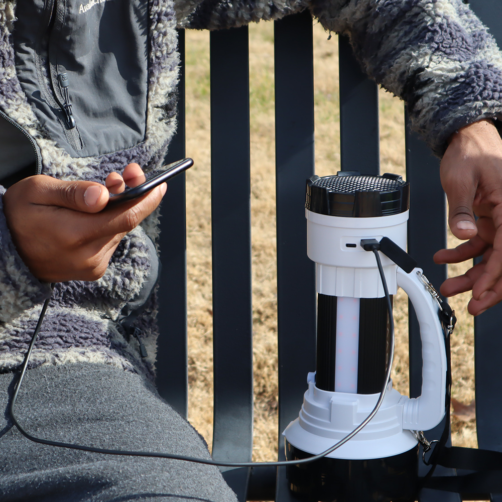Person using a smartphone with a black and white device on a metal fence background