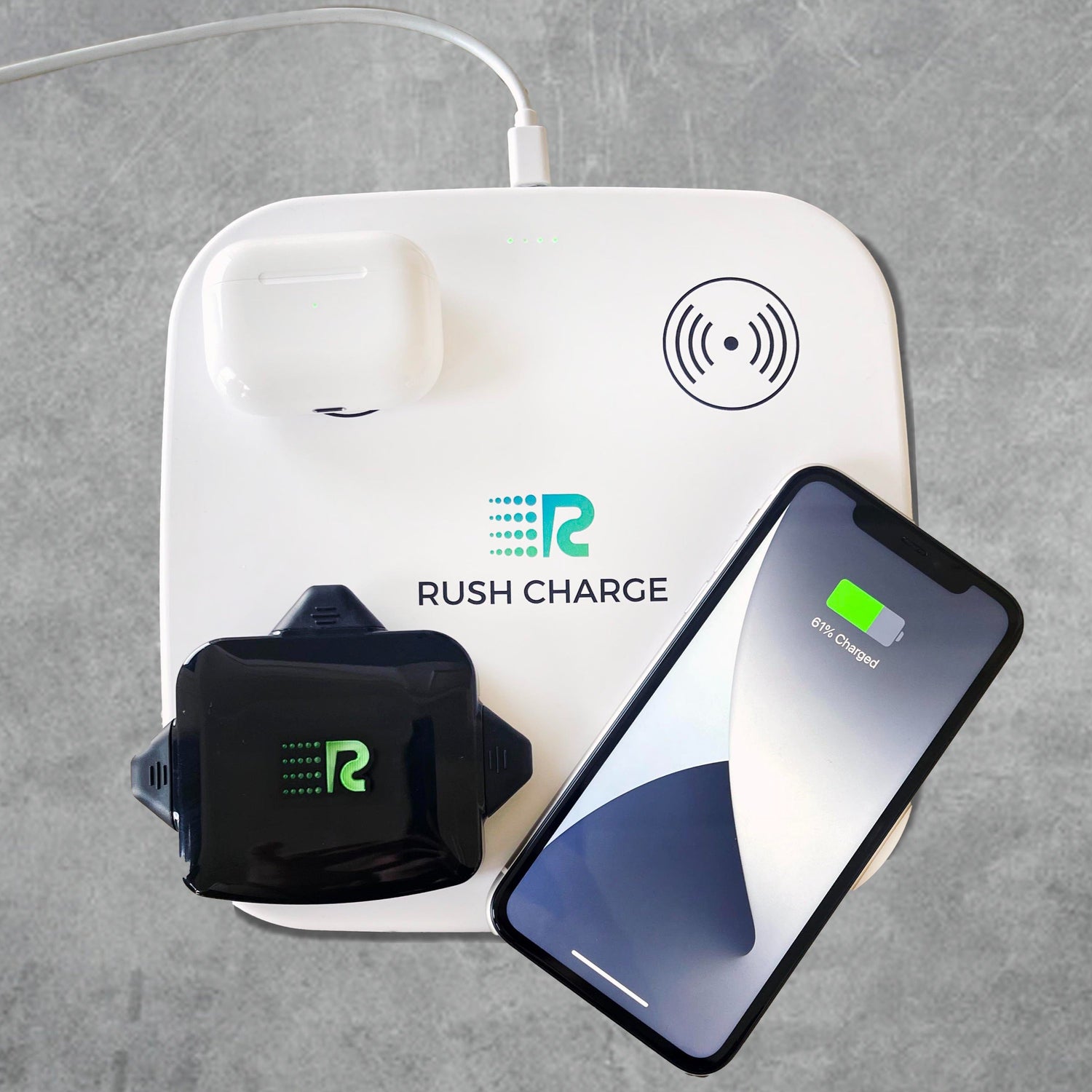 Rush Charge wireless charging pad with phone and earbuds on a gray background