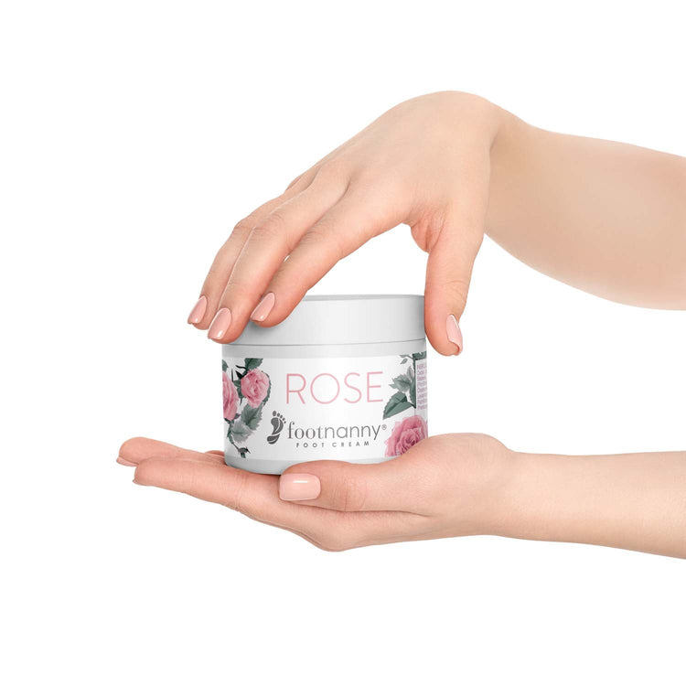Hand holding a jar of 'Footnanny Rose' foot cream against a white background