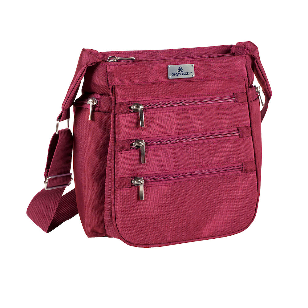 A person walking away from the camera wearing a blue shirt and carrying a black crossbody daybag with shoulder strap.