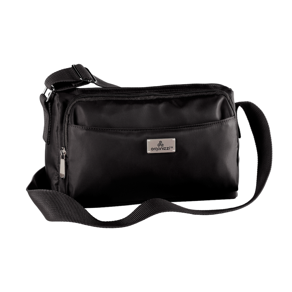 A person seated on a bench with a striped skirt and a black top, wearing a blue crossbody bag with multiple compartments.