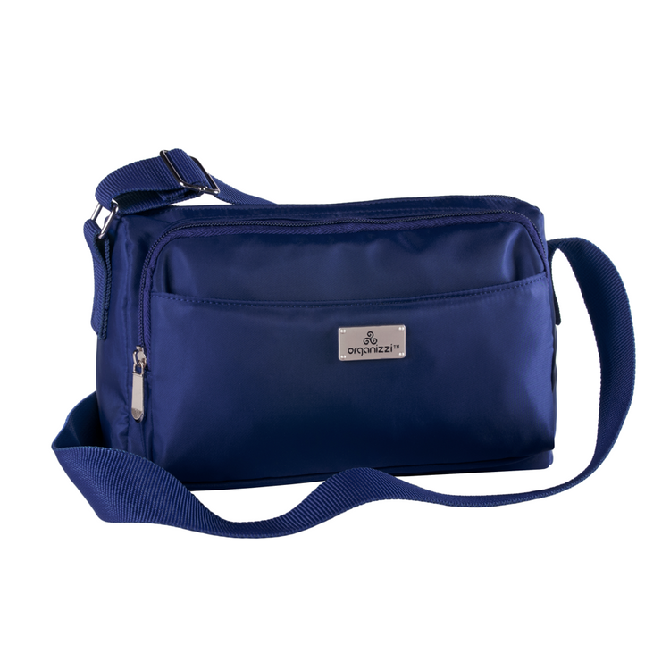 A person seated on a bench with a striped skirt and a black top, wearing a blue crossbody bag with multiple compartments.