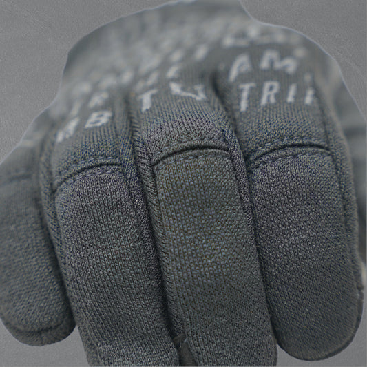 Man wearing ear protection, sunglasses, and gloves outdoors with a clear sky.