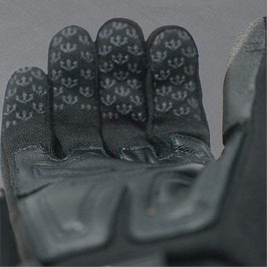 Man wearing ear protection, sunglasses, and gloves outdoors with a clear sky.