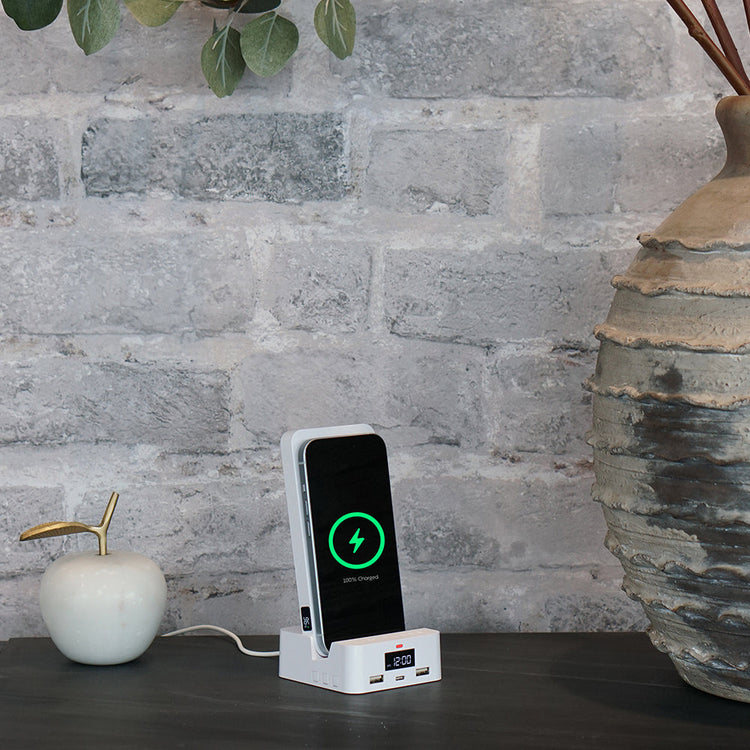 Phone charging station with smartphone on a wooden surface against a stone wall background