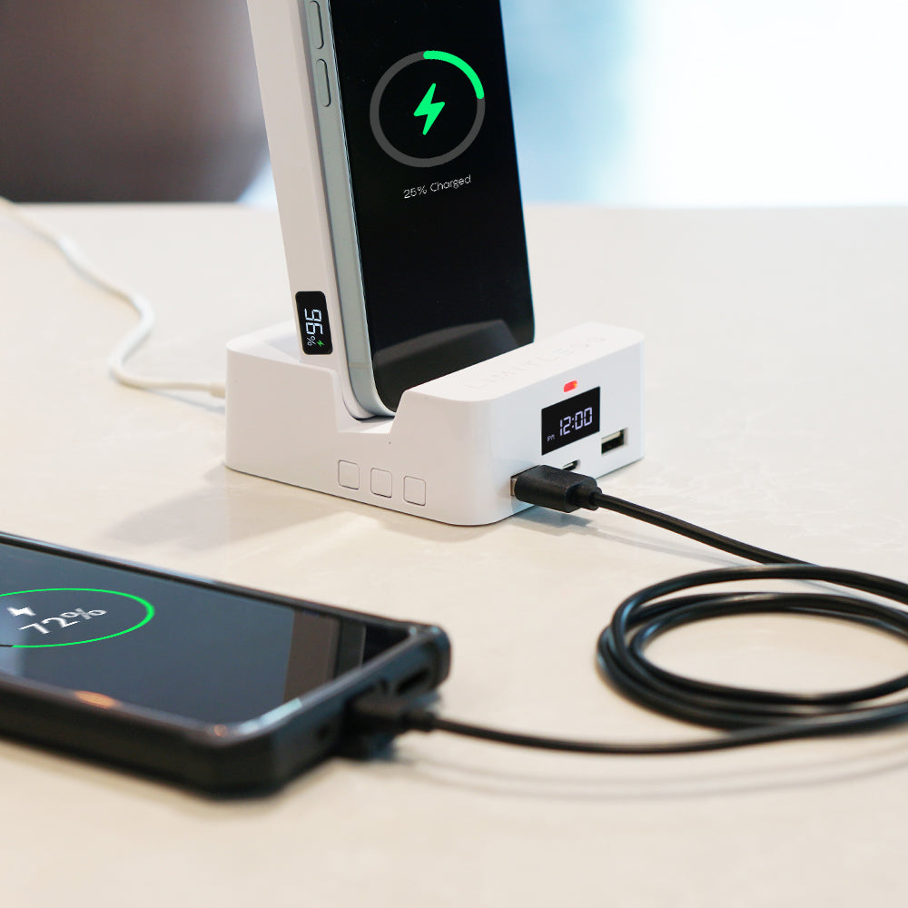 Smartphone charging on a dock with digital display on a light surface.