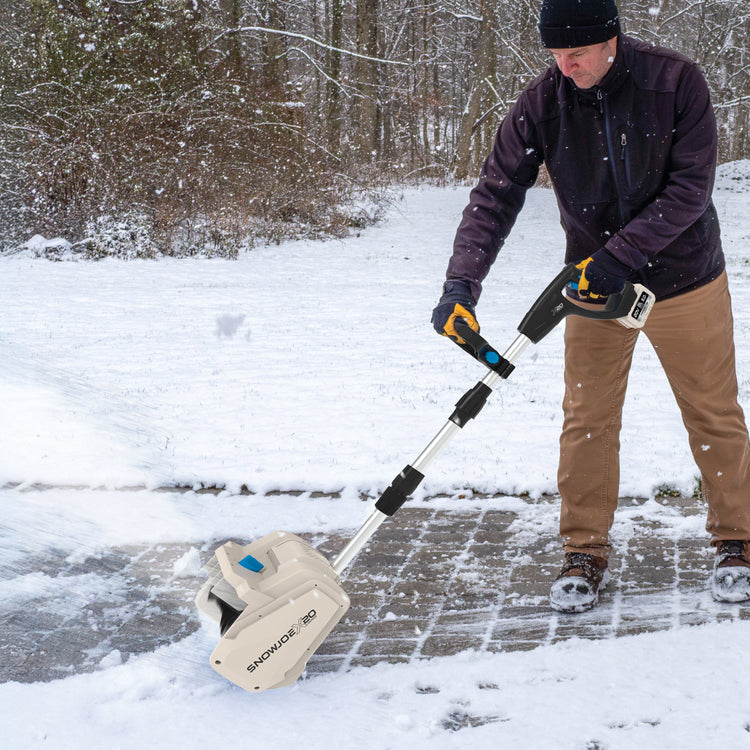 Person using a snow removal tool on a snowy driveway
