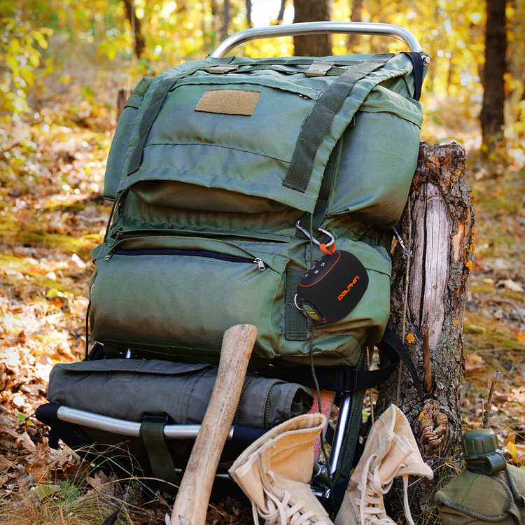 Green backpack with hiking gear in a forest setting