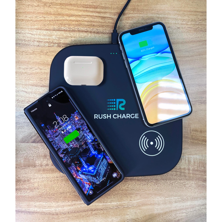 Wireless charging pad with two smartphones and a wireless earbuds case on a wooden surface, branded 'Rush Charge'.