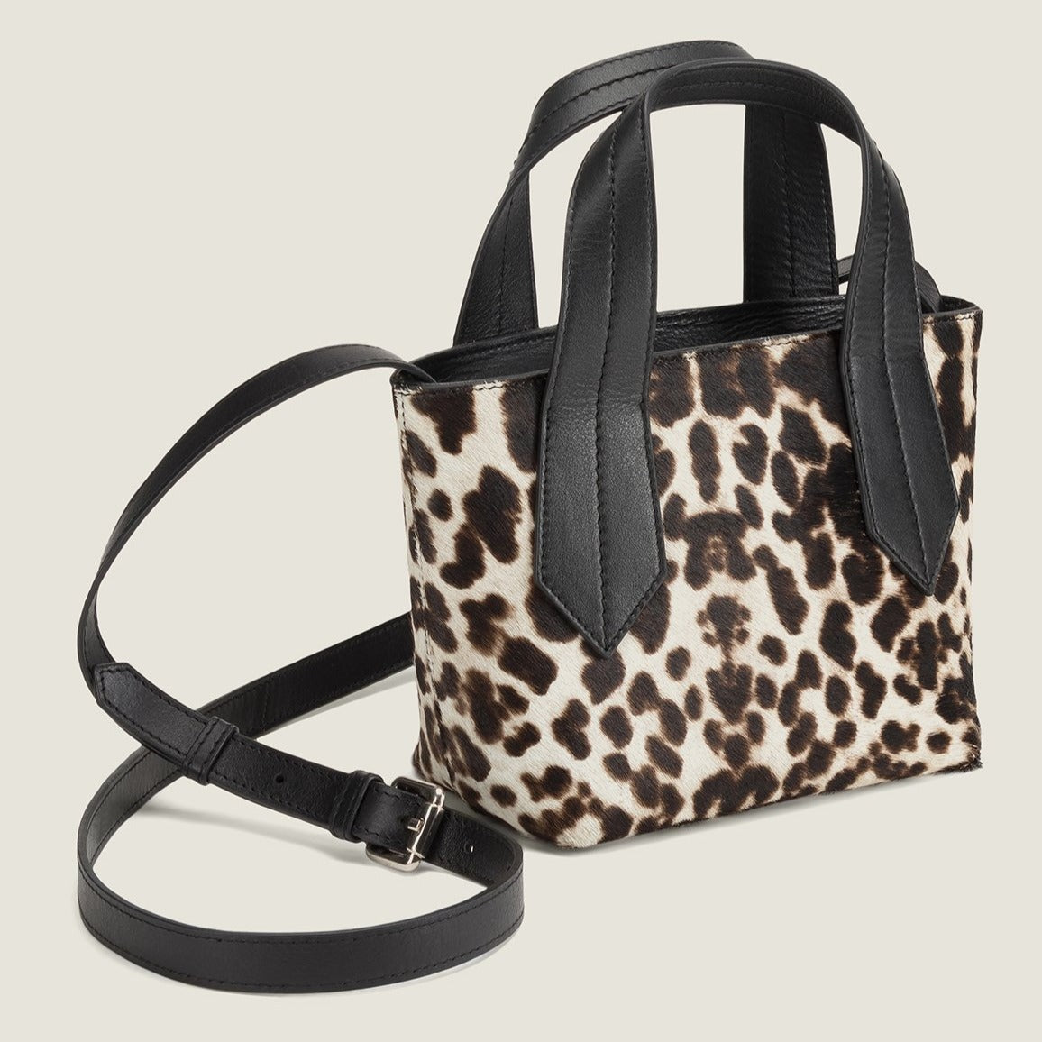 SIDE SHOT OF THE TAB TOTE MINI IN SNOW LEOPARD AND LEATHER CROSSBODY STRAP